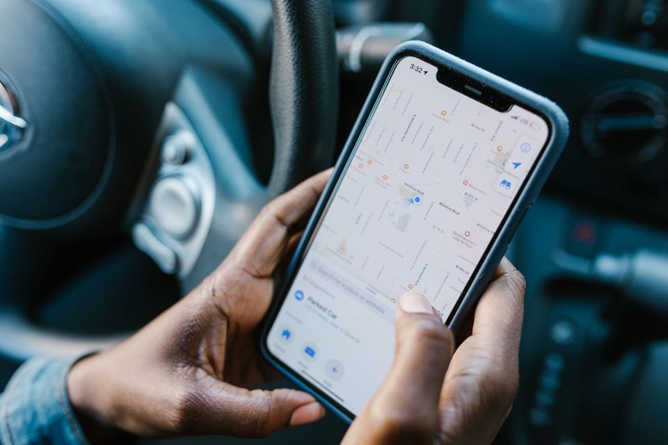 A person checking a business location on a Google Maps app on their phone, standing in for a contractor monitoring how their listing actually appears to customers.