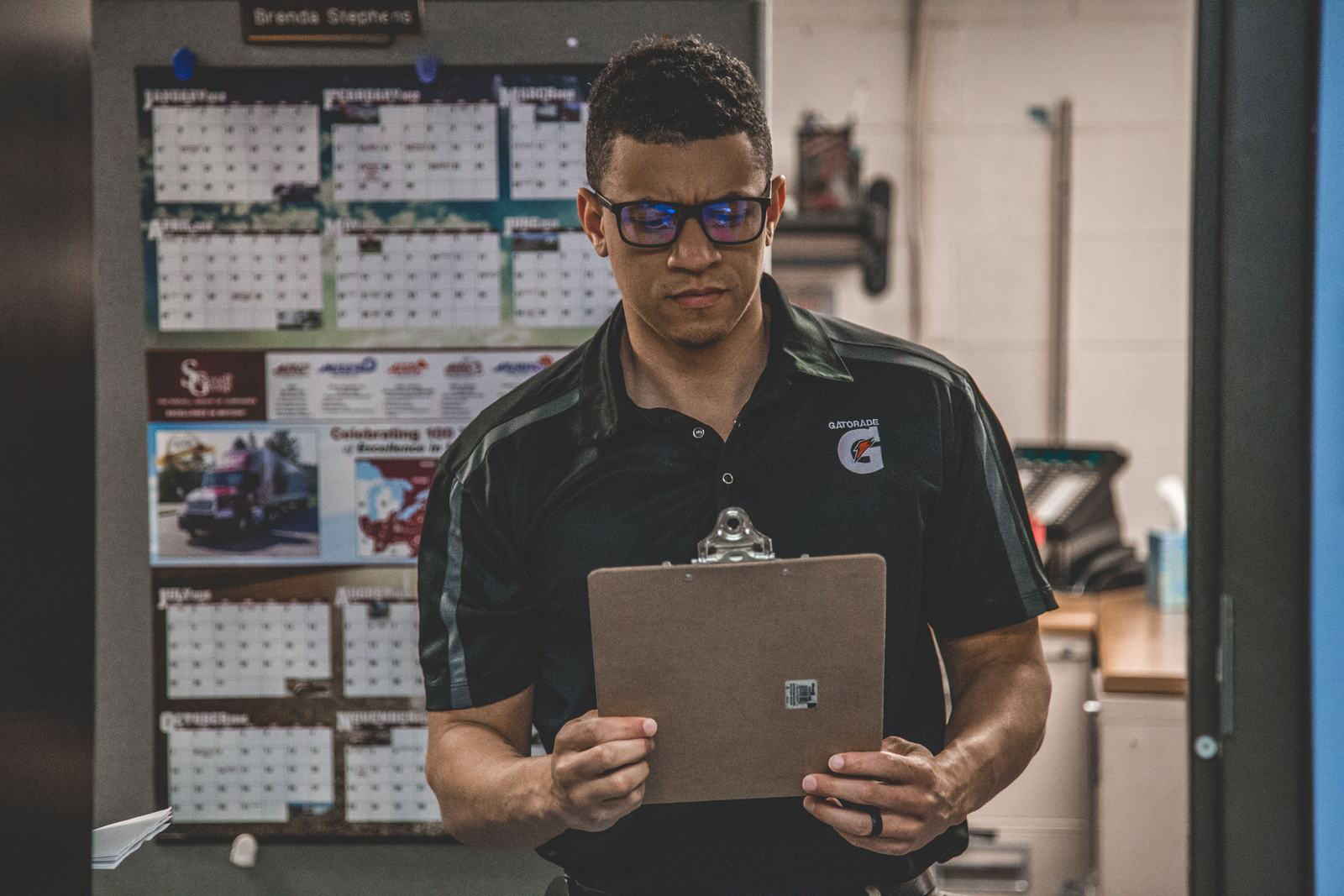 A worker in a shop reviewing a document on a clipboard, standing in for reading a lead platform's membership and cancellation terms closely before signing up.