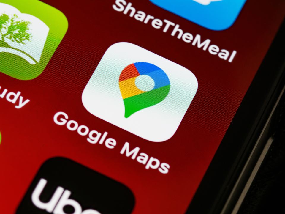 The Google Maps app icon on a phone screen, standing in for the actual data source a voice assistant reads from to answer a local search.