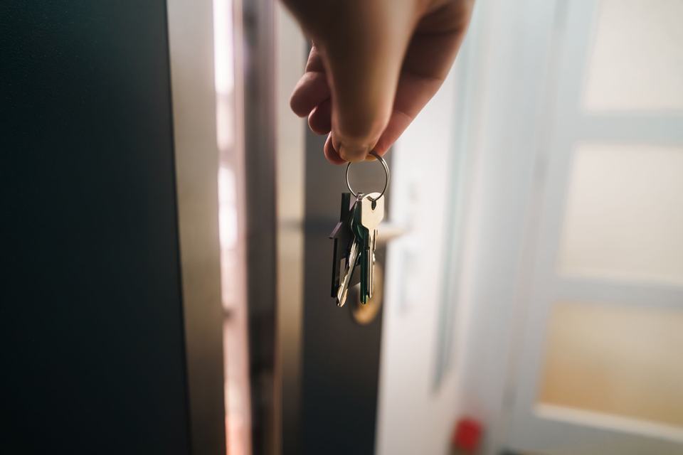 A hand holding keys at a new doorway, standing in for a business owner about to update their Google Business Profile after a move.