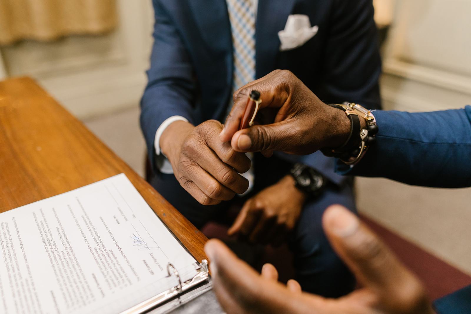Two people reviewing and signing a document at a desk, standing in for reading a Houzz Pro subscription's renewal terms before agreeing to them.