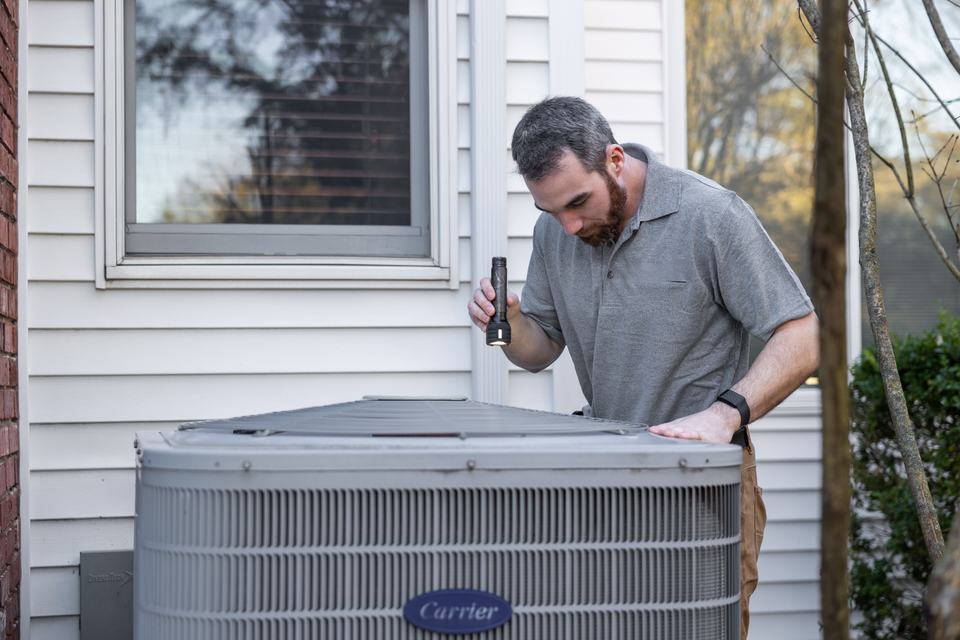A technician finishing an HVAC inspection at a real house, standing in for the moment right before the truck leaves, the natural point to log a photo.
