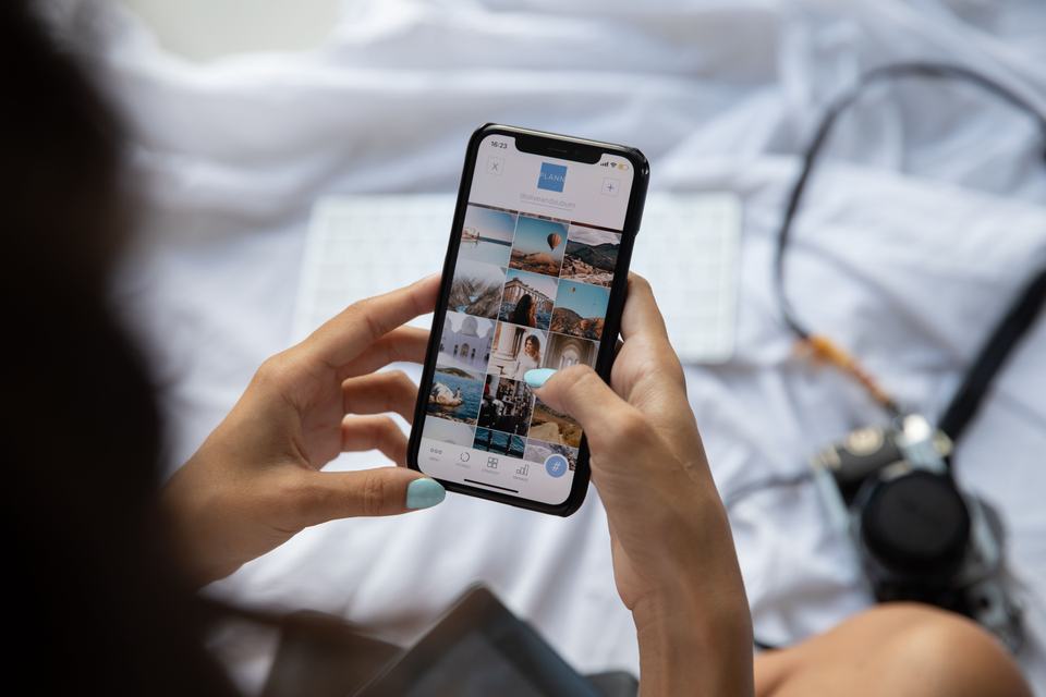 A hand scrolling a phone showing social content, standing in for posting real job photos instead of generic stock graphics.