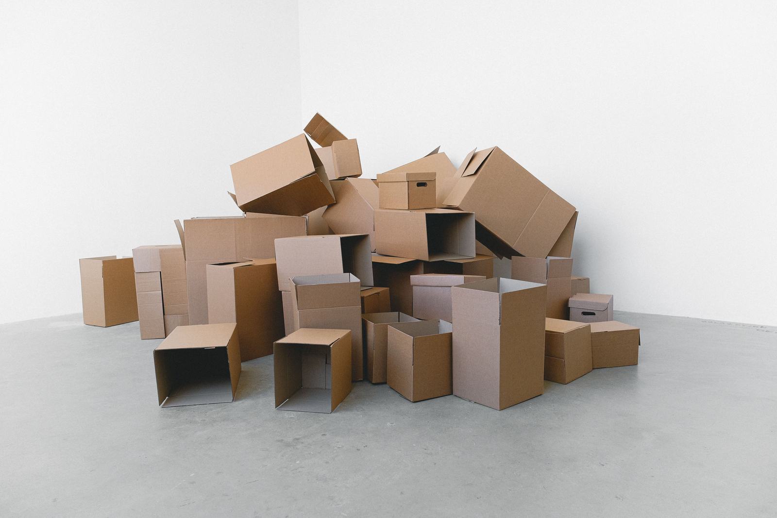 A pile of moving boxes in an empty room, standing in for a business relocating and needing to update its Google Business Profile address.