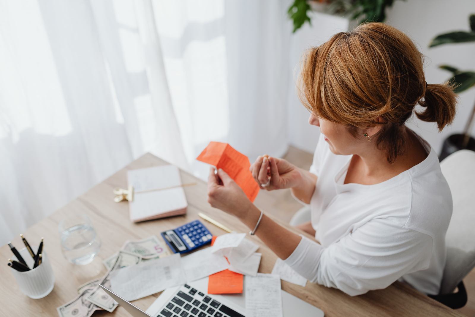 A woman reviewing utility bills and receipts at a desk, standing in for a business owner checking whether their paperwork matches their Google Business Profile.
