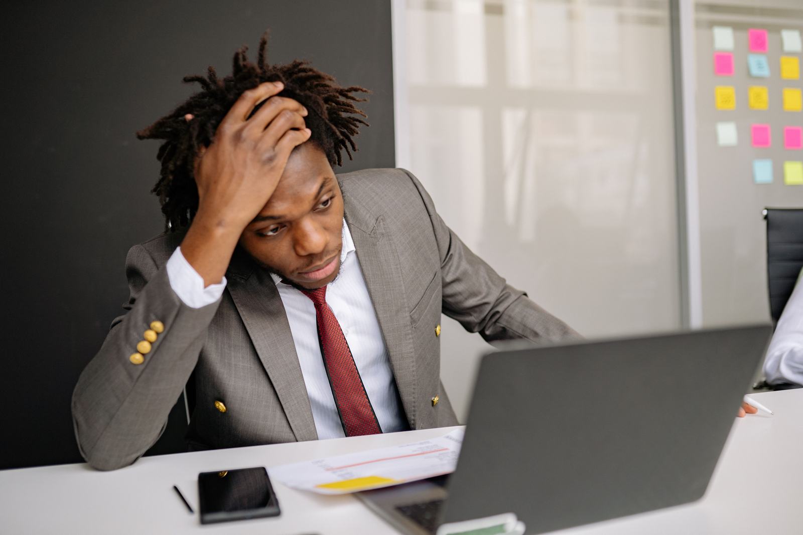 A business owner in a suit holding his head while looking at a laptop screen, standing in for the moment a Google Business Profile goes down without warning.