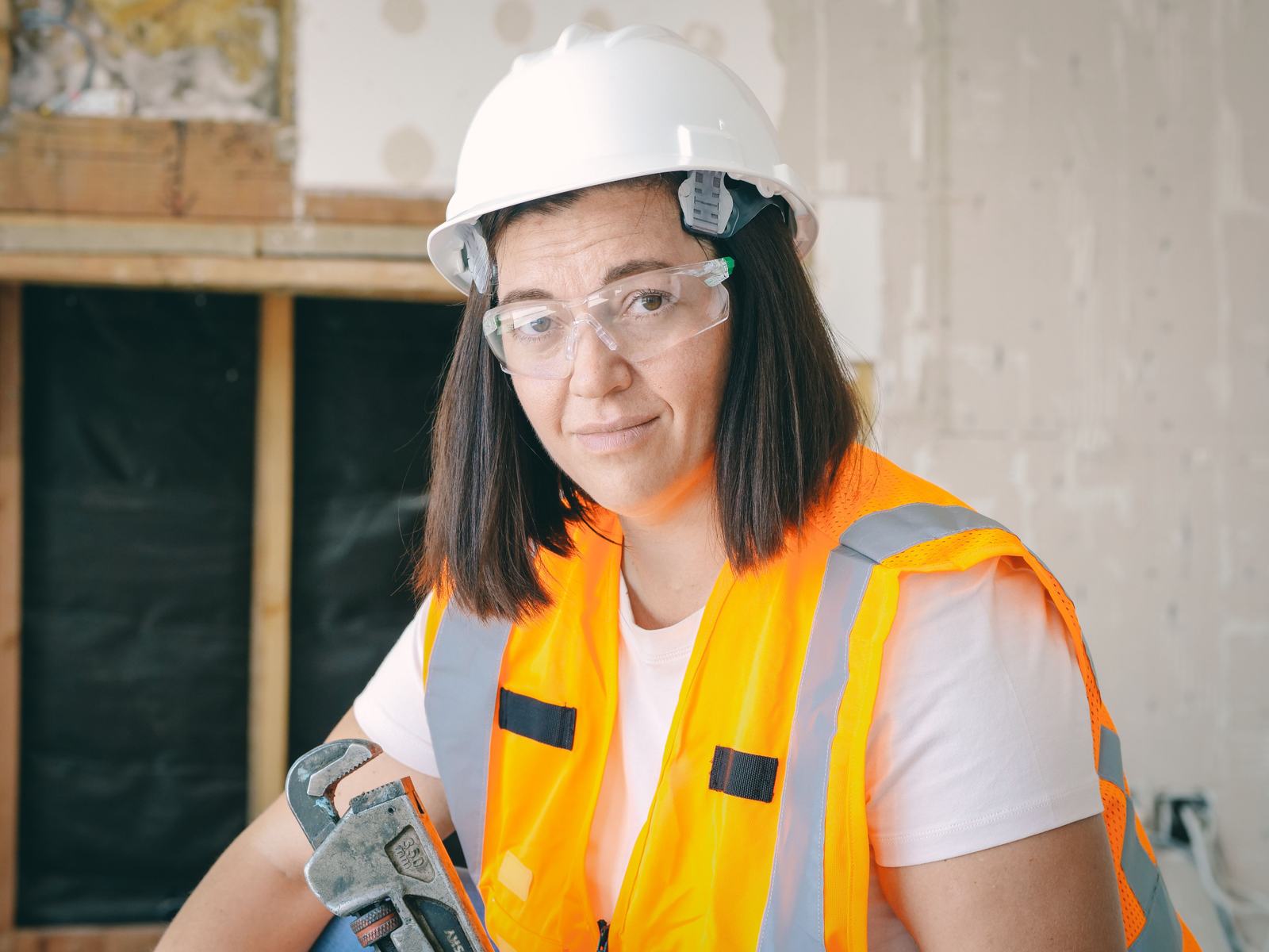 A tradesperson holding a wrench at a job site, standing in for the real, dated work a Business Profile needs proof of.