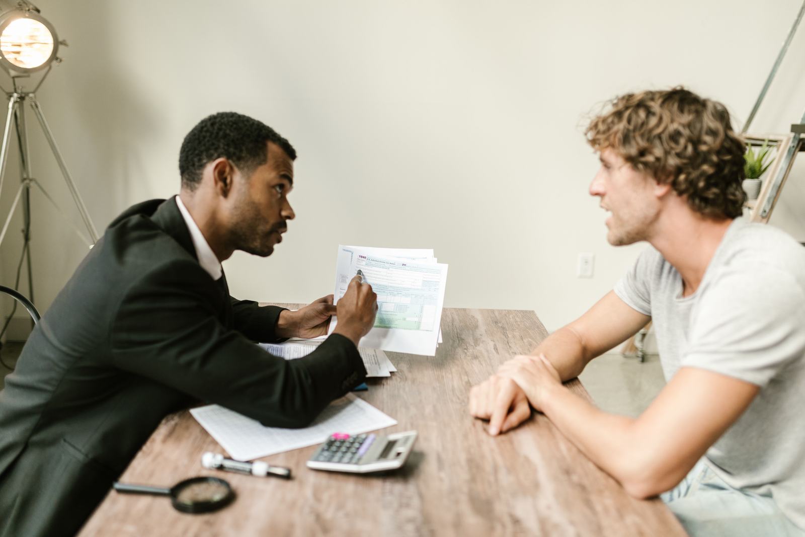 A financial advisor reviewing paperwork with a client at a desk, standing in for a buyer's due diligence team checking where a business's leads actually come from.