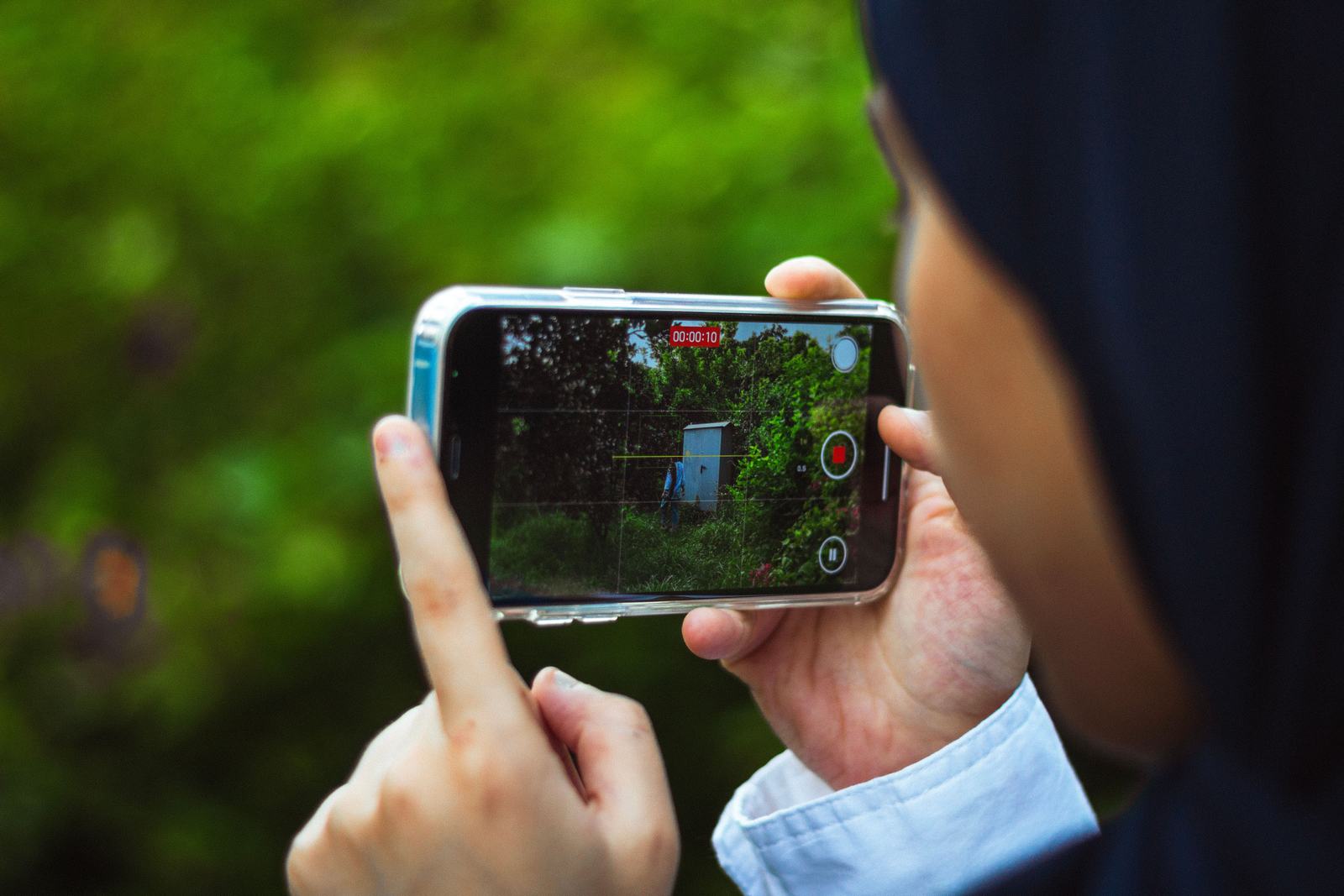 A person filming a live video outdoors on a smartphone, standing in for recording a Google Business Profile verification video.